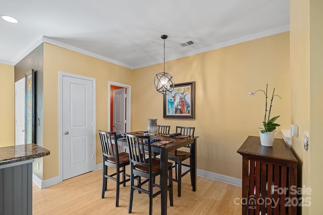 dining area with a chandelier, ornamental molding, and light hardwood / wood-style flooring