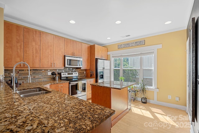 kitchen featuring stainless steel appliances, a center island, dark stone counters, sink, and backsplash