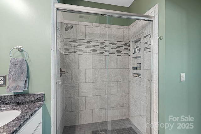 bathroom featuring a shower with door and vanity