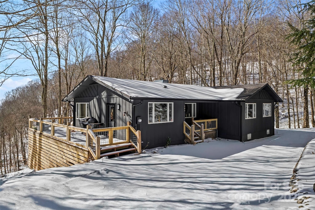 snow covered back of property with a wooden deck