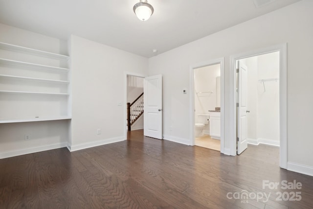 interior space featuring ensuite bathroom, built in desk, dark hardwood / wood-style flooring, a spacious closet, and a closet