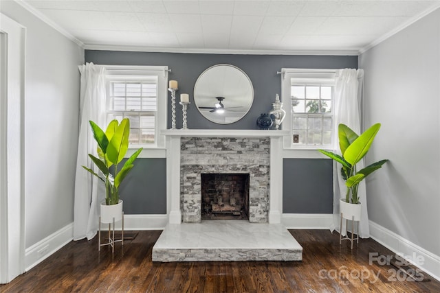 living room featuring ceiling fan, a stone fireplace, ornamental molding, and dark wood-type flooring