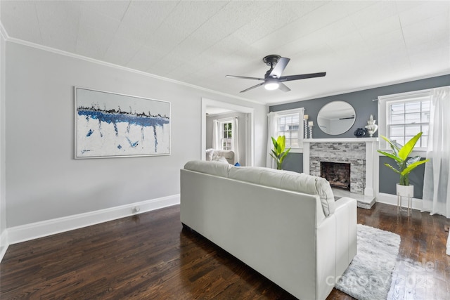 living room featuring crown molding, ceiling fan, a fireplace, and dark wood-type flooring