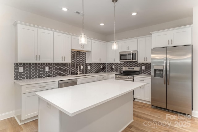 kitchen featuring white cabinetry, hanging light fixtures, stainless steel appliances, and sink