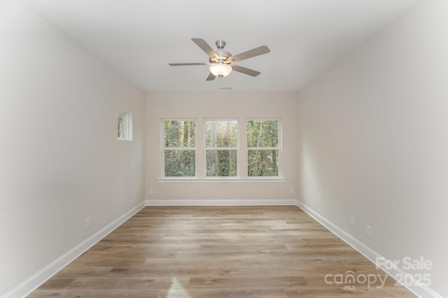 unfurnished room with a ceiling fan, light wood-style flooring, and baseboards