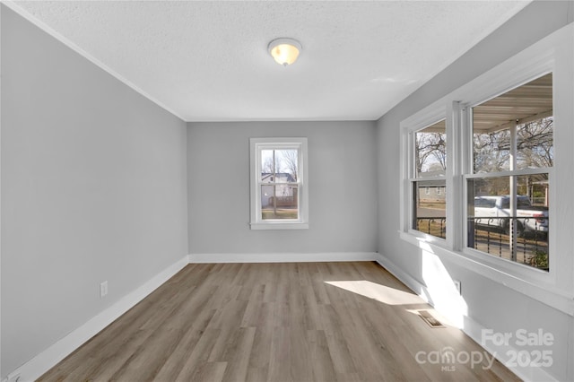 spare room featuring a textured ceiling and light wood-type flooring