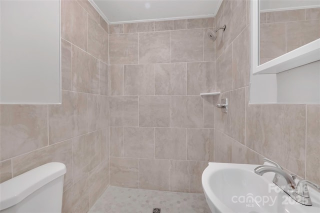 bathroom with sink, toilet, and a tile shower