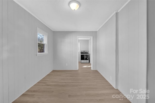 corridor with wood walls, ornamental molding, and light wood-type flooring