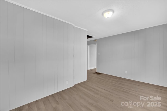 unfurnished room featuring wood walls and light hardwood / wood-style flooring