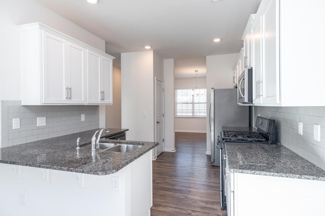 kitchen with sink, a breakfast bar area, dark stone countertops, white cabinetry, and stainless steel appliances