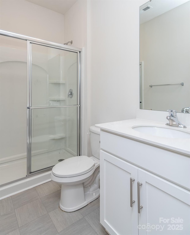 bathroom featuring tile patterned flooring, vanity, a shower with shower door, and toilet