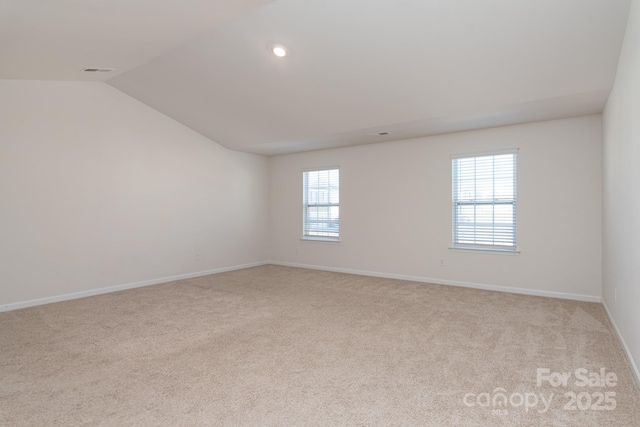 empty room featuring light colored carpet and lofted ceiling