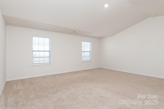 carpeted spare room featuring lofted ceiling and a healthy amount of sunlight