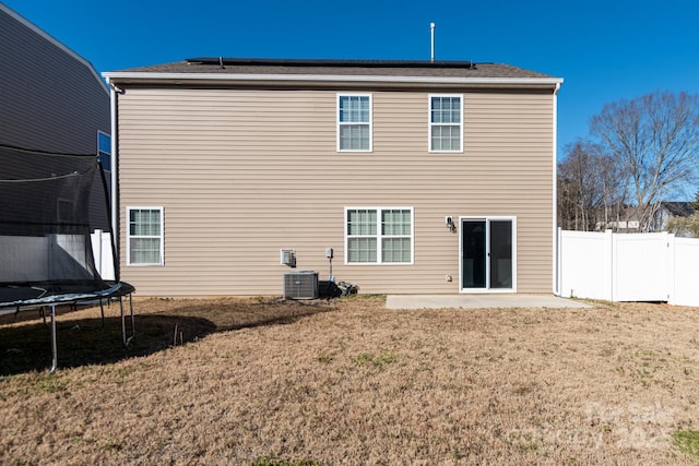 rear view of property featuring a lawn, a patio area, cooling unit, and a trampoline