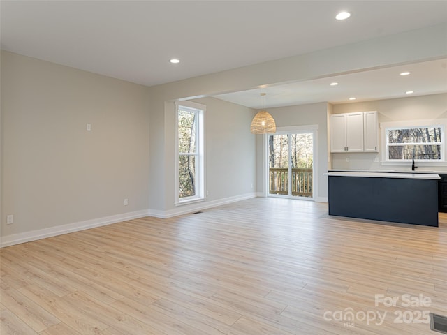 unfurnished living room featuring light hardwood / wood-style floors and sink