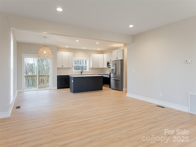 kitchen with white cabinetry, a center island, stainless steel appliances, pendant lighting, and light hardwood / wood-style floors