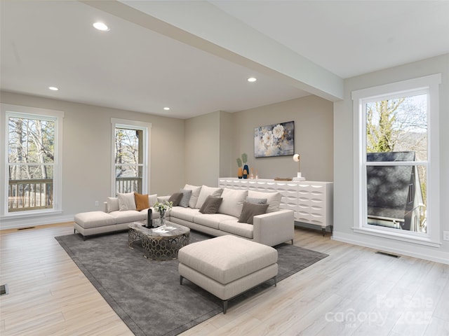 living room featuring beam ceiling and light wood-type flooring