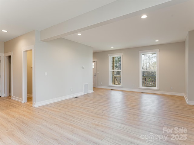 unfurnished room with beam ceiling and light hardwood / wood-style floors