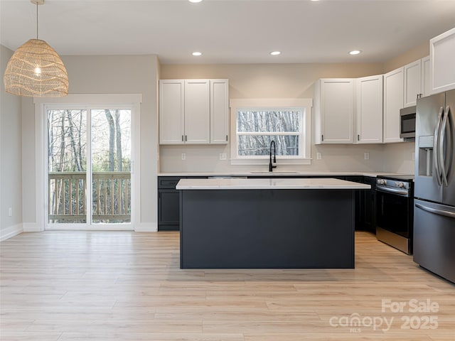 kitchen featuring a center island, white cabinets, hanging light fixtures, sink, and appliances with stainless steel finishes