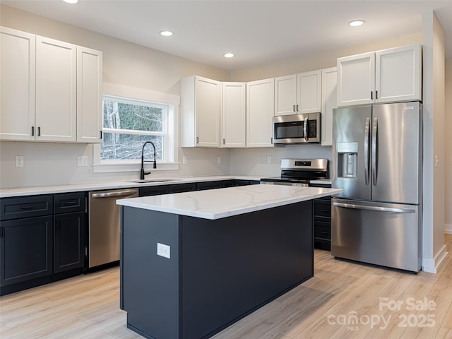 kitchen with appliances with stainless steel finishes, a center island, light hardwood / wood-style floors, and sink