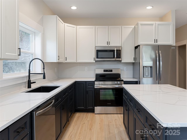 kitchen featuring white cabinetry, light stone counters, sink, and appliances with stainless steel finishes