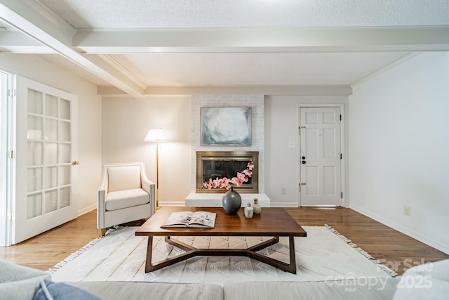 living room with a fireplace, beamed ceiling, a textured ceiling, and hardwood / wood-style flooring