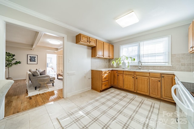 kitchen with light tile patterned floors, tasteful backsplash, ornamental molding, range, and sink