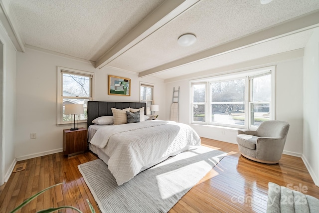 bedroom featuring beamed ceiling, a textured ceiling, and hardwood / wood-style floors