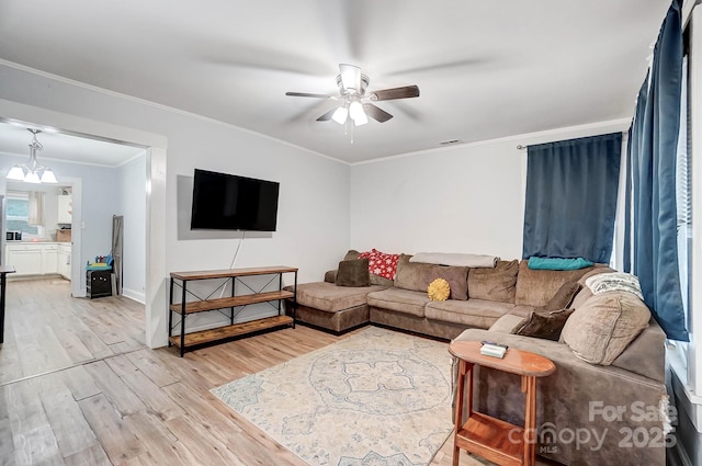 living room featuring ceiling fan with notable chandelier, light hardwood / wood-style floors, and ornamental molding