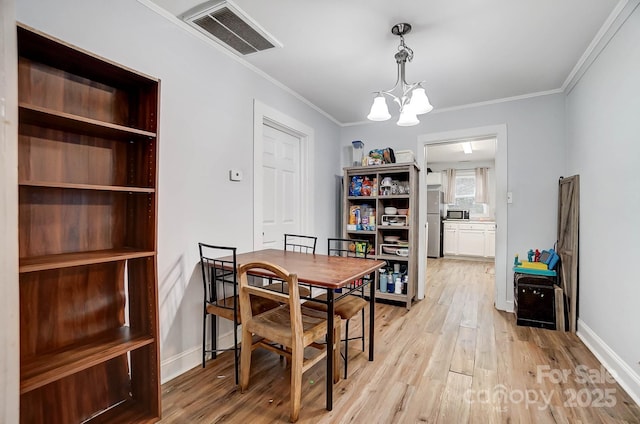 dining space with light wood-type flooring, an inviting chandelier, and crown molding