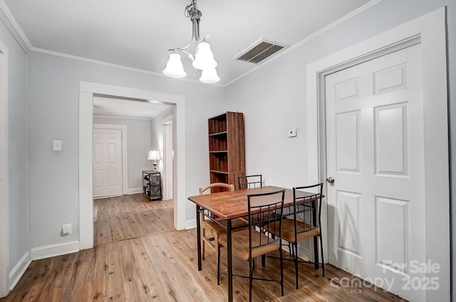 dining area with light hardwood / wood-style flooring, ornamental molding, and an inviting chandelier