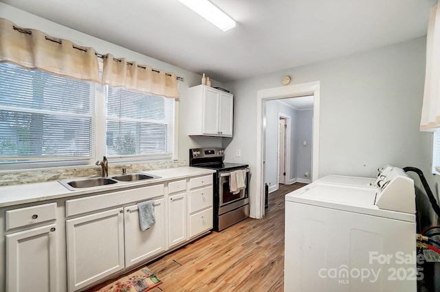 kitchen featuring stainless steel electric range, white cabinets, sink, separate washer and dryer, and light hardwood / wood-style floors