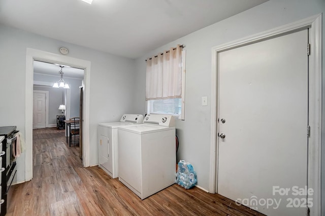 laundry room featuring light wood-type flooring, washing machine and dryer, and an inviting chandelier