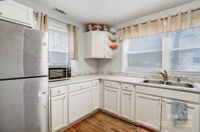 kitchen featuring stainless steel appliances, white cabinetry, light hardwood / wood-style floors, and sink