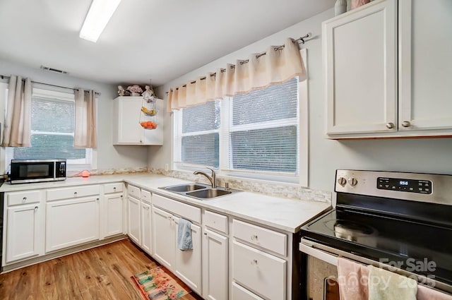 kitchen with a wealth of natural light, white cabinetry, sink, and stainless steel appliances