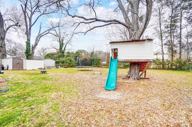 view of yard featuring a storage shed, a playground, and a trampoline