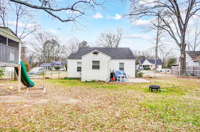 rear view of house with a sunroom, an outdoor fire pit, a yard, a playground, and a patio