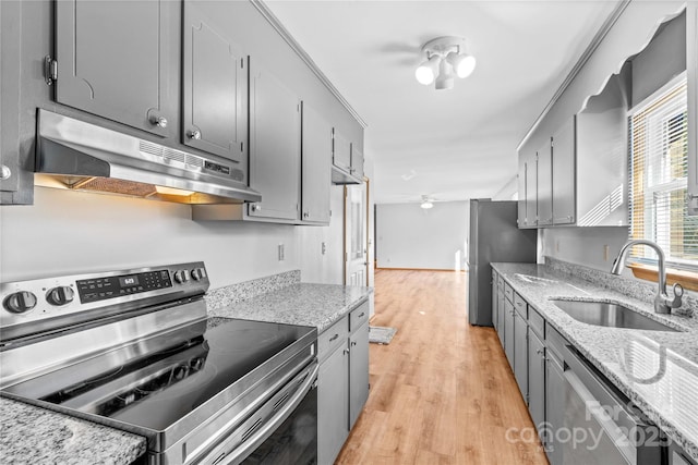 kitchen with light stone countertops, sink, stainless steel appliances, and light wood-type flooring