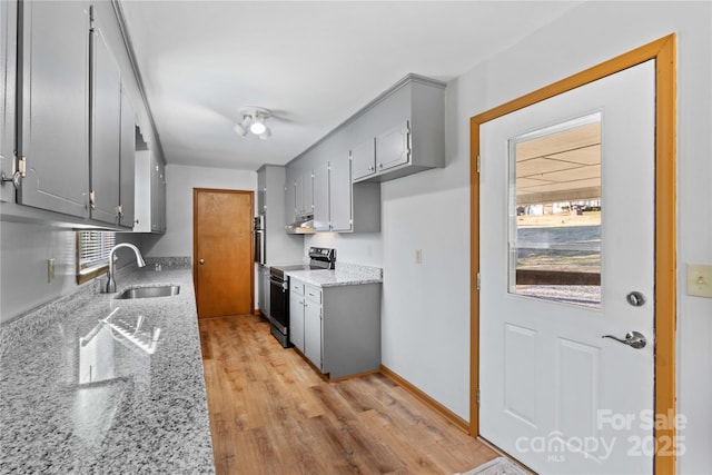 kitchen featuring stainless steel electric stove, light stone counters, sink, and light hardwood / wood-style flooring