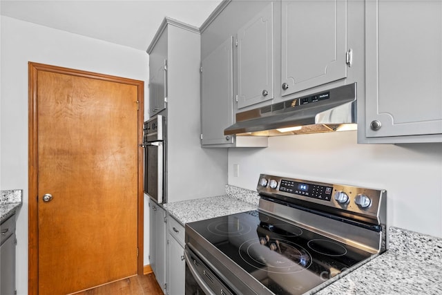 kitchen with stainless steel electric stove, light stone countertops, oven, and light wood-type flooring