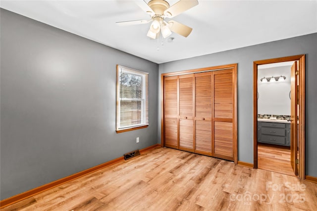 unfurnished bedroom featuring connected bathroom, a closet, light hardwood / wood-style flooring, and ceiling fan