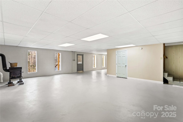 basement with a wood stove and a drop ceiling