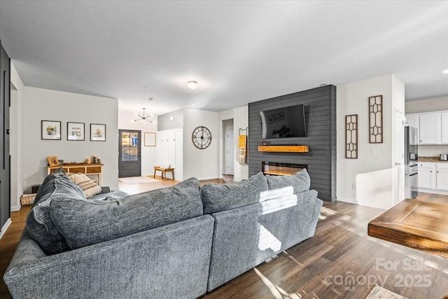 living room featuring a large fireplace, dark hardwood / wood-style flooring, and an inviting chandelier