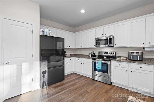 kitchen featuring white cabinets, appliances with stainless steel finishes, dark hardwood / wood-style flooring, and dark stone counters