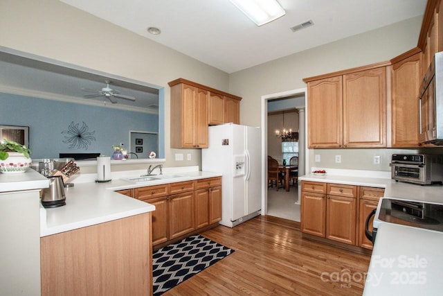 kitchen with sink, light hardwood / wood-style flooring, kitchen peninsula, white appliances, and ceiling fan with notable chandelier