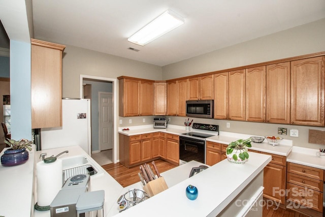 kitchen with sink, electric range, light wood-type flooring, and white fridge