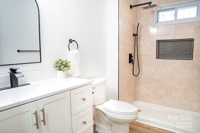 bathroom with vanity, a tile shower, and toilet