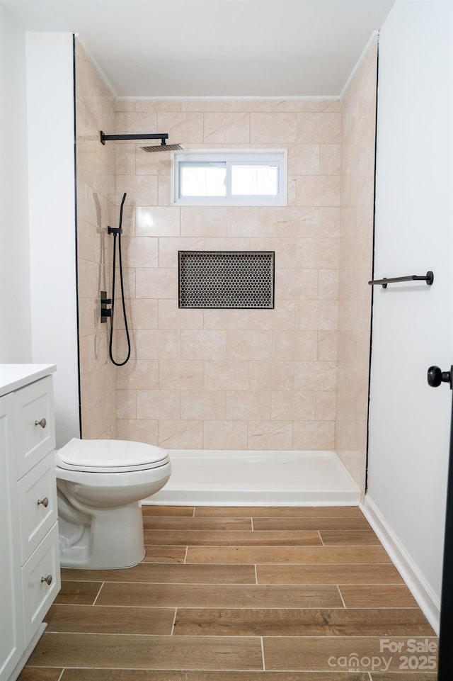 bathroom with vanity, a tile shower, and toilet