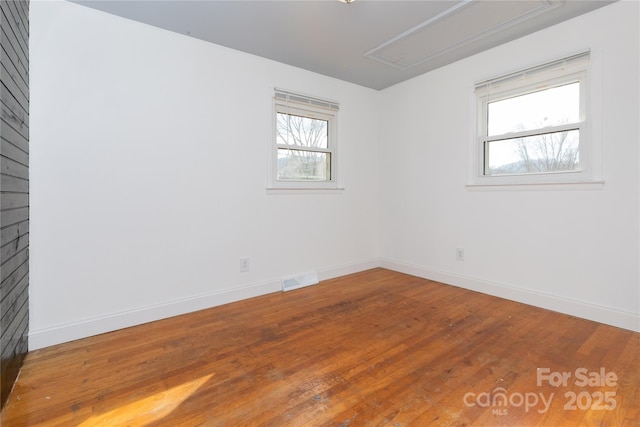 empty room with hardwood / wood-style flooring and a healthy amount of sunlight