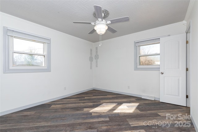 spare room featuring crown molding, a healthy amount of sunlight, and dark hardwood / wood-style flooring